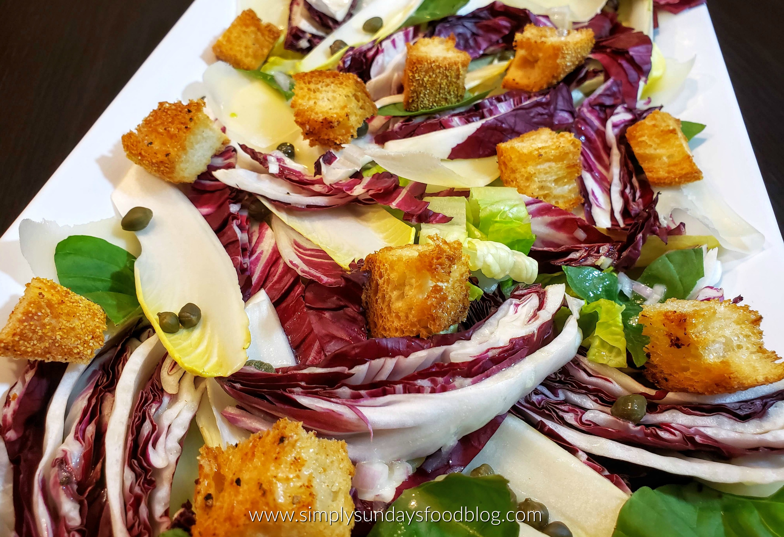 A platter of mild romaine lettuce, bold radicchio and crisp endive with crunchy homemade croutons, creamy parmesan drizzled with dijon vinaigrette